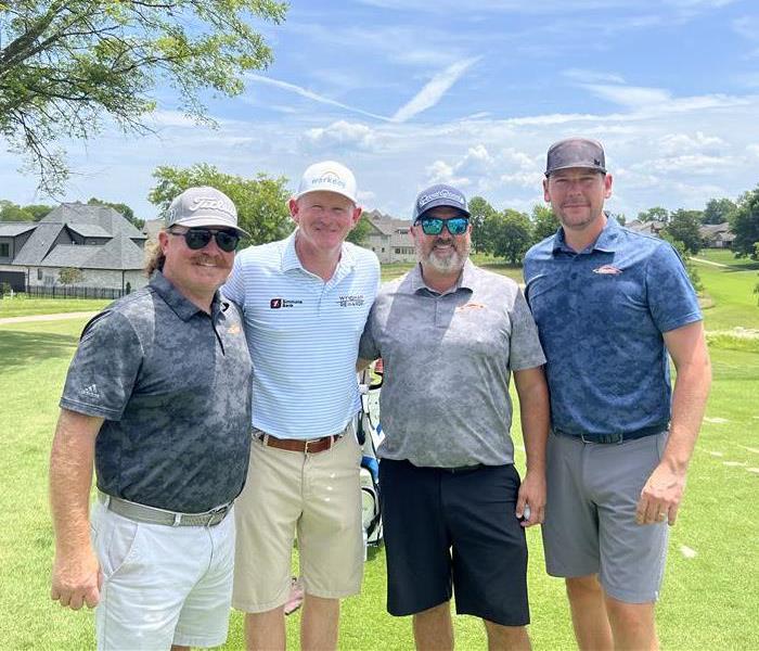 Four men in golf attire on golf course